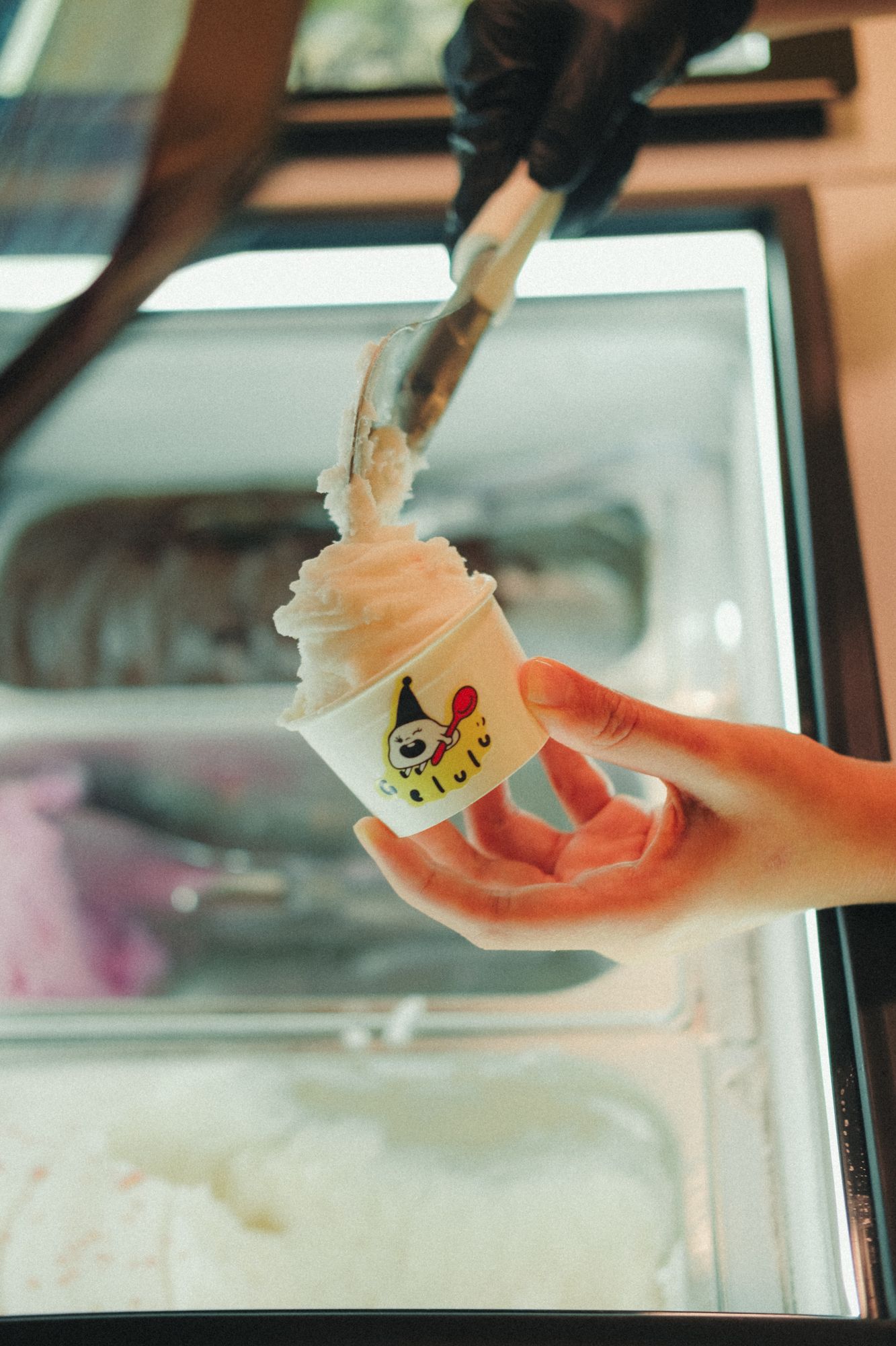 Scooping gelato into a Gelulu cup at the cabinet